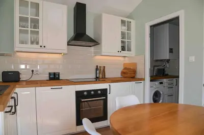 a kitchen with white cabinets and a wooden table at The Restoration Place Pyrenees in Roquefixade