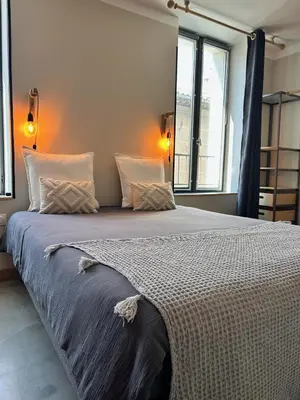 a large bed in a bedroom with two windows at Côté Nuit in Capestang