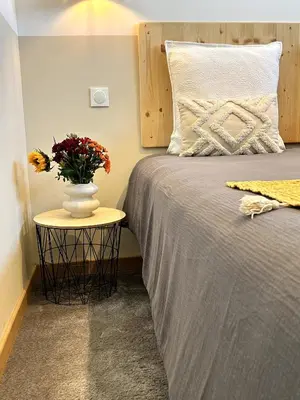 a bedroom with a bed with a vase of flowers on a table at Côté Nuit in Capestang