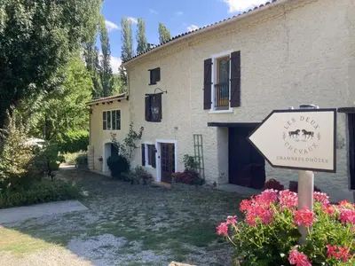 a house with a sign in front of it at Les Deux Chevaux Chambres d’Hôtes in Rouvenac