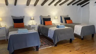 a room with three beds with blue and orange pillows at Les Deux Chevaux Chambres d’Hôtes in Rouvenac