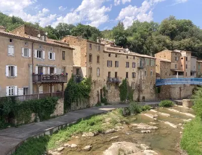 a group of buildings next to a river at Les Deux Chevaux Chambres d’Hôtes in Rouvenac