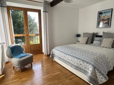 a bedroom with a bed and a chair and a window at Les Deux Chevaux Chambres d’Hôtes in Rouvenac