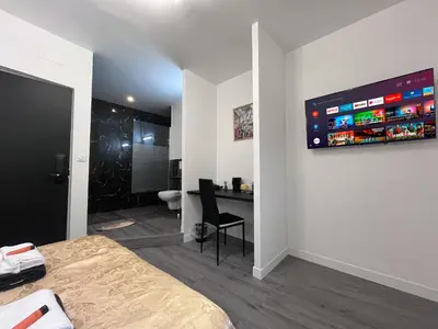 a bedroom with a bed and a desk and a monitor on the wall at Cosy Centre Ville Narbonne in Narbonne