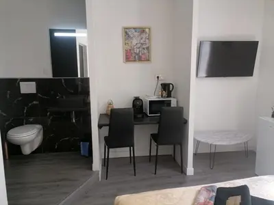 a room with a desk with chairs and a microwave at Cosy Centre Ville Narbonne in Narbonne