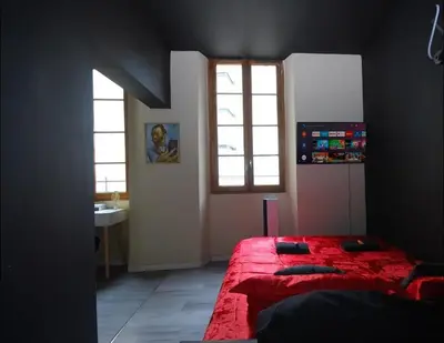 a bedroom with a red bed and a window at Baignoire Cosy Centre Narbonne in Narbonne