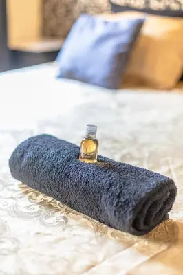a blue blanket on a bed with a bottle of perfume at Studio Baignoire centre ville in Narbonne