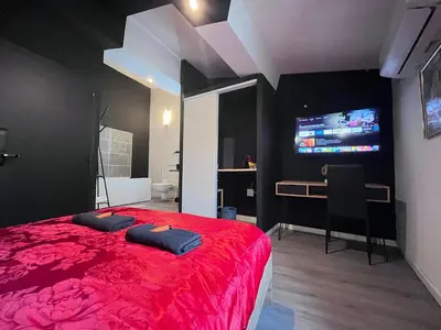 a bedroom with a red bed and a desk and a tv at Studio Baignoire centre ville in Narbonne