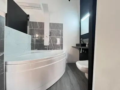 a white bathroom with a tub and a toilet at Charmant Studio Baignoire in Narbonne