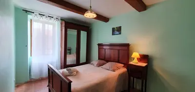 a bedroom with a bed and a lamp and a window at La maison de mon enfance ! Au cœur du Minervois ! in Félines-Minervois