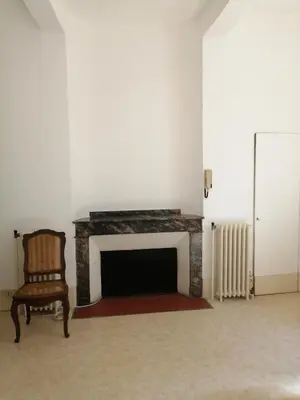 a room with a fireplace with a chair and a radiator at Maison Alba La Source in Mazamet