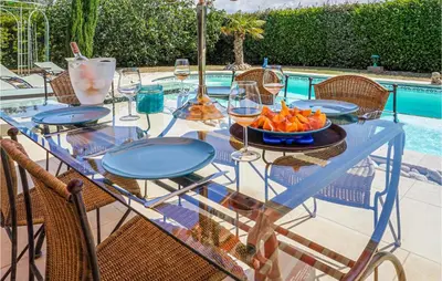 a glass table with a bowl of fruit on it next to a pool at Beautiful Home In Carcassonne in Carcassonne