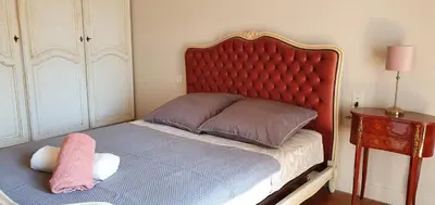 a bed with a red headboard and a pink pillow at La casa de Margarita y Sisco, Villa avec piscine in Carcassonne
