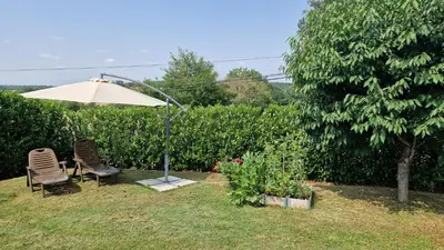 two chairs and an umbrella in a yard at Chambre d'hôte Lempautoise in Lempaut