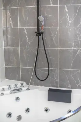 a white bath tub with a shower in a bathroom at Jacuzzi Terrasse Centre Narbonne in Narbonne