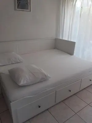 a white bed with two pillows on top of it at Studio Grazel classé 1 étoile au calme Rez de chaussée avec piscine et jardin in Gruissan