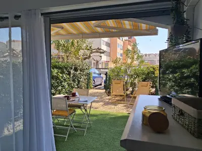 a patio with a table and chairs on grass at Studio Grazel classé 1 étoile au calme Rez de chaussée avec piscine et jardin in Gruissan