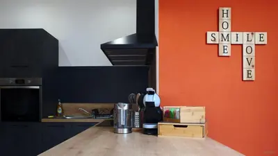a kitchen with an orange wall and a counter top at T2 chaleureux au centre de castelnaudary in Castelnaudary