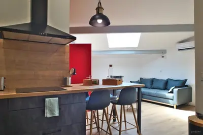 a kitchen with a bar with chairs and a couch at T2 chaleureux au centre de castelnaudary in Castelnaudary