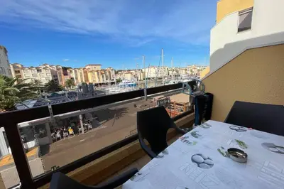 a balcony with a table and a view of a harbor at Appartement terrasse sur le port, piscine, tennis in Gruissan