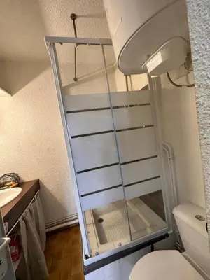 a glass shower door in a bathroom next to a toilet at Appartement terrasse sur le port, piscine, tennis in Gruissan