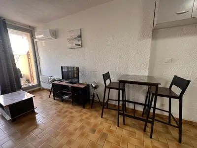 a living room with a table and chairs and a desk at Appartement terrasse sur le port, piscine, tennis in Gruissan
