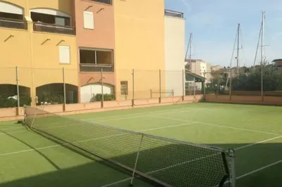 a tennis court in front of a building at Appartement terrasse sur le port, piscine, tennis in Gruissan