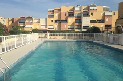 a large swimming pool in front of a building at Appartement terrasse sur le port, piscine, tennis in Gruissan