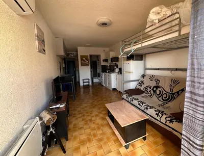 a living room with a couch and a bunk bed at Appartement terrasse sur le port, piscine, tennis in Gruissan