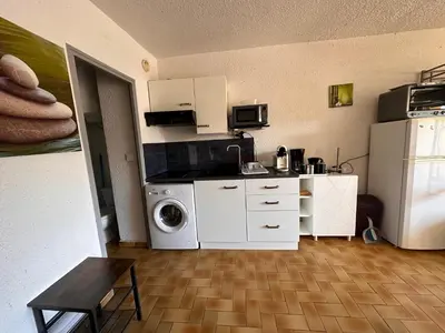 a kitchen with a washing machine and a refrigerator at Appartement terrasse sur le port, piscine, tennis in Gruissan
