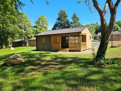 a small cabin in a yard with a tree at Au bois de Mars in Les Martys