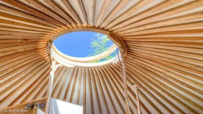 a round window in a wooden yurt with a window at Au bois de Mars in Les Martys