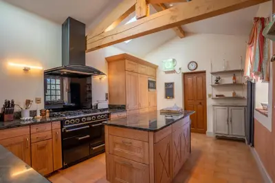 a large kitchen with wooden cabinets and a stove at Les Cazettes in Damiatte