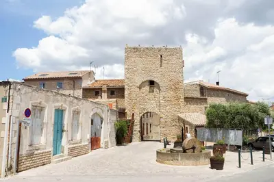 an old stone building with a tower on a street at La Porte du Midi in Mailhac