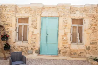 a stone building with a blue door and two windows at La Porte du Midi in Mailhac