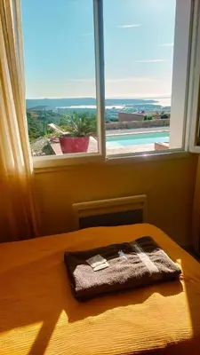 a blanket on a bed in front of a window at Maison avec vue sur la mer et avec piscine à Fitou in Fitou