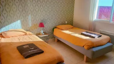a bedroom with two beds with orange sheets and a lamp at Maison avec vue sur la mer et avec piscine à Fitou in Fitou