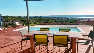 a wooden table and chairs on a deck with a pool at Maison avec vue sur la mer et avec piscine à Fitou in Fitou