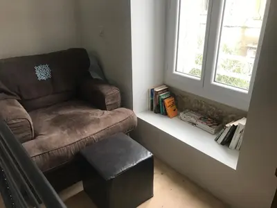 a brown chair sitting next to a window with a stool at L Ostalada in Roquefort-des-Corbières