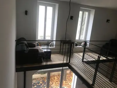 a room with a balcony with a bed and windows at L Ostalada in Roquefort-des-Corbières