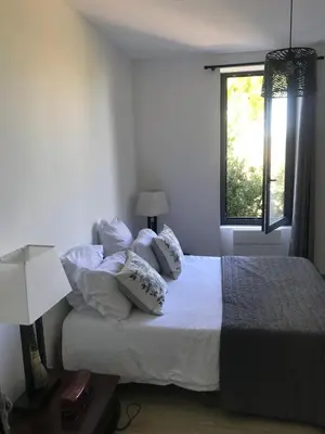 a bedroom with a bed with pillows and a window at L Ostalada in Roquefort-des-Corbières