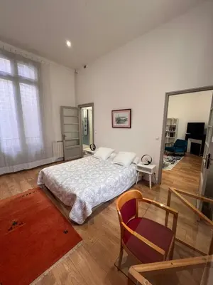 a bedroom with a bed and a mirror and a chair at Les clématites in Narbonne