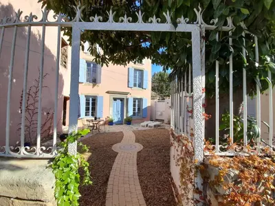 an entrance to a garden with a white fence at La maison SPA, PISCINE et CLIMATISATION in Sainte-Vallière