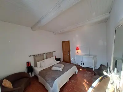 a bedroom with a bed and a chair and a desk at La maison SPA, PISCINE et CLIMATISATION in Sainte-Vallière