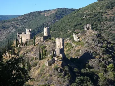 a castle on top of a mountain with trees at Domaine Les Cascades in Ribaute