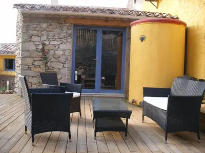 a patio with chairs and a table on a wooden deck at Domaine Les Cascades in Ribaute