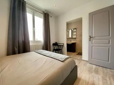 a bedroom with a bed with blue pillows and a window at Maison Tommy in Carcassonne