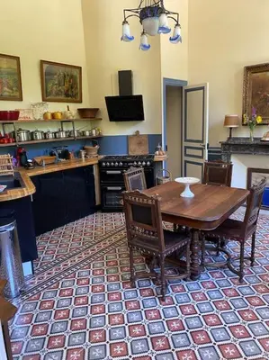 a kitchen with a wooden table and chairs in it at Maison d'Hôtes de La Rivière in Pexiora