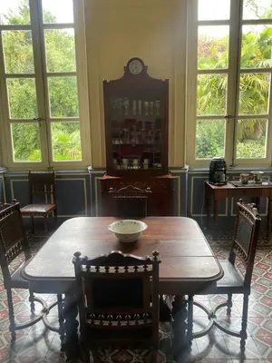 a dining room with a table and chairs and a clock at Maison d'Hôtes de La Rivière in Pexiora