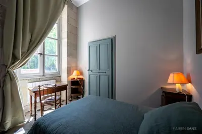 a bedroom with a bed and a desk and a window at Maison d'Hôtes de La Rivière in Pexiora